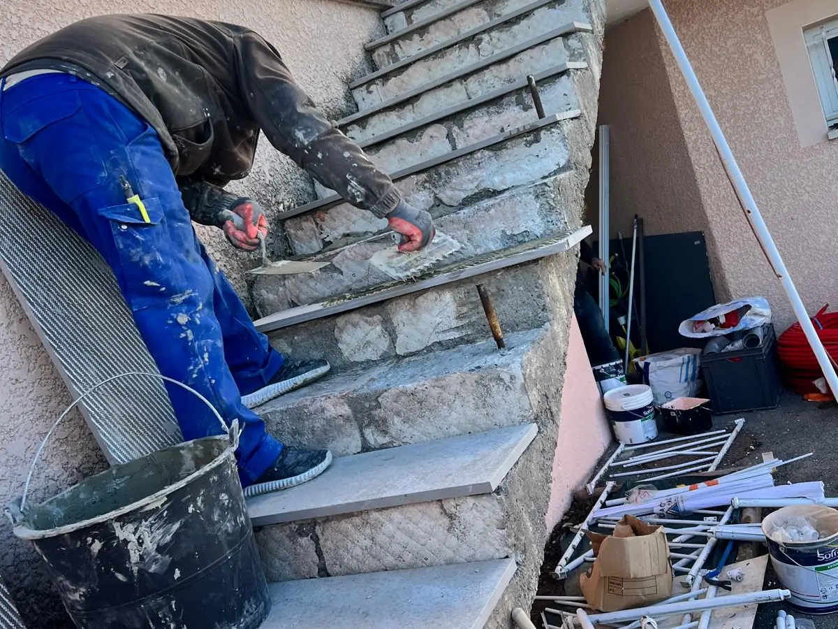 Artisan en train de poser les marches en pierre d'un escalier extérieur
