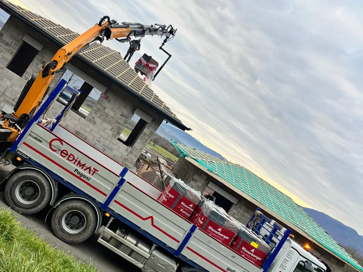 Livraison de matériaux par camion-grue sur une maison en construction