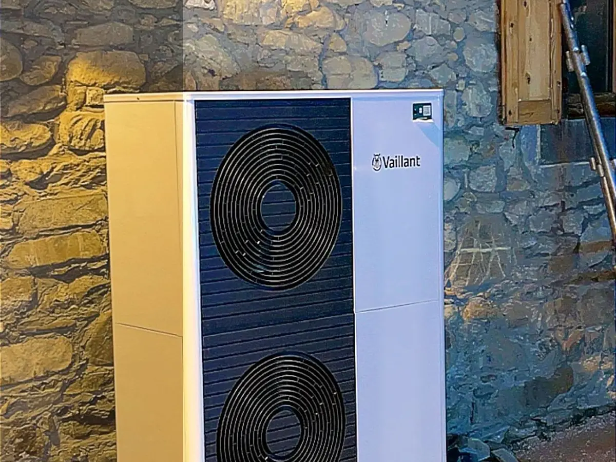 Pompe à chaleur installée contre un mur en pierre lors d'une rénovation